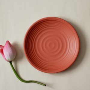 pink and white flower bud beside round red round plate